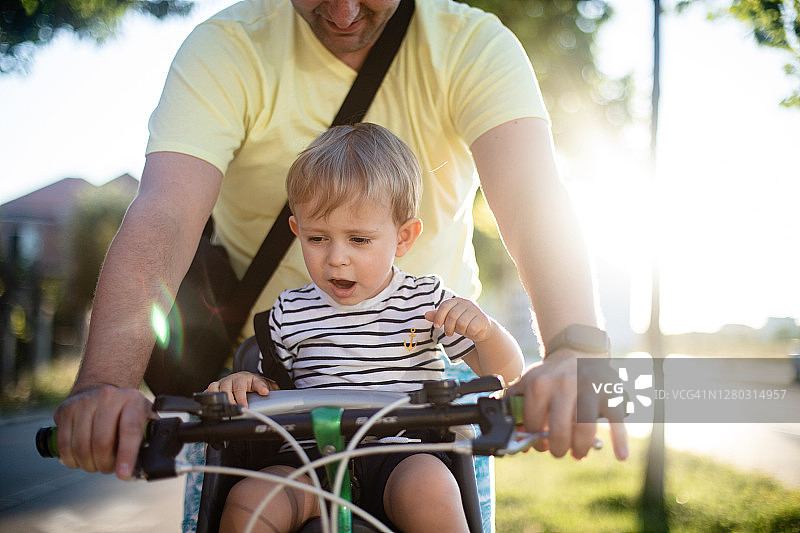 父亲骑自行车，儿子坐在座位上图片素材