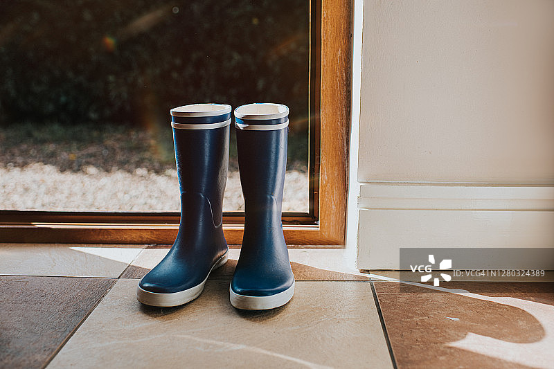 蓝色惠灵顿靴子靠在敞开的后门旁图片素材