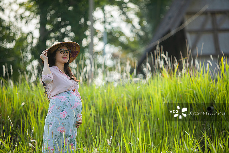 稻田里和传统房屋中的亚洲孕妇图片素材