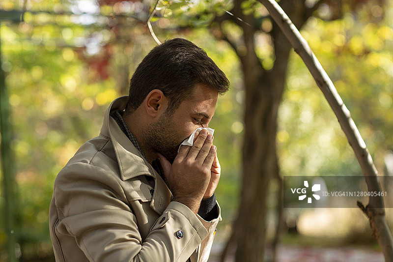 在户外擤鼻涕的黄发男子图片素材