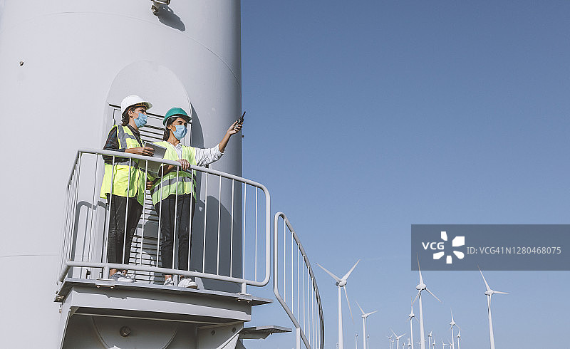 戴口罩的女维护工程师在风力发电场维护风力涡轮机图片素材