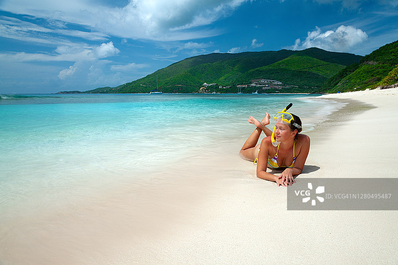 戴着呼吸管和面罩的女人在热带海滩岸边休息图片素材