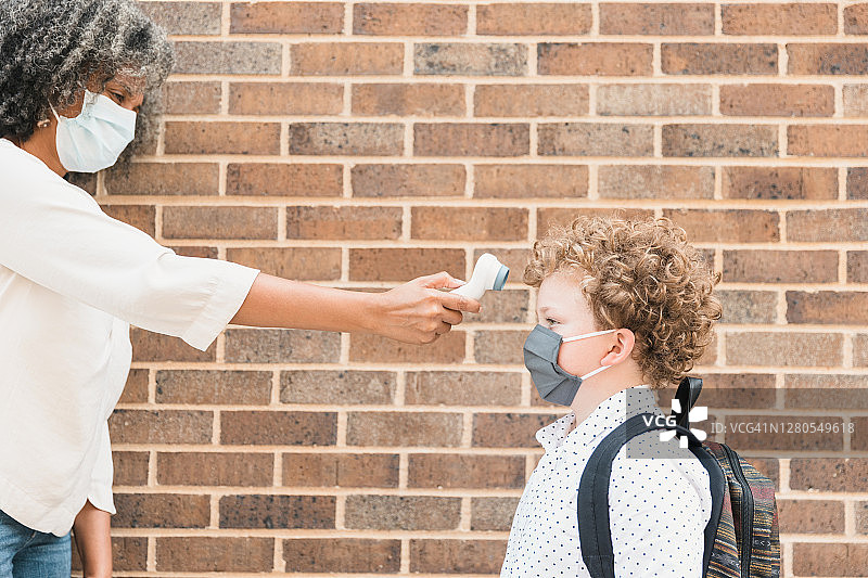 新冠疫情期间老师检查学生的体温图片素材