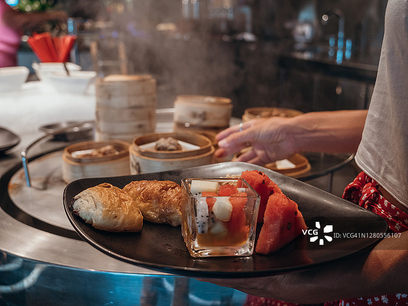 自助餐取餐的女人，旁有亚洲饺子图片素材