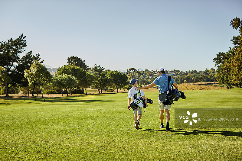 夏天，高尔夫球手和男孩走在草地上图片素材