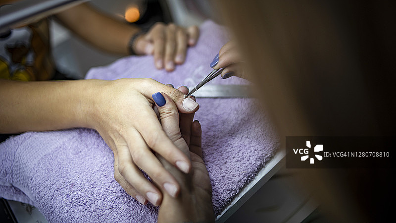 美容院中的美甲过程 - 美甲师为女性顾客修指甲图片素材