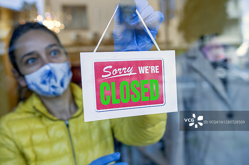 店主在商店门口翻转“已关闭”标志图片素材