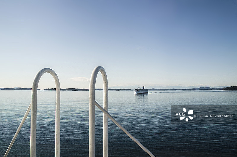 晴朗的一天，两艘渡轮在加拿大不列颠哥伦比亚省平静的水域中航行图片素材