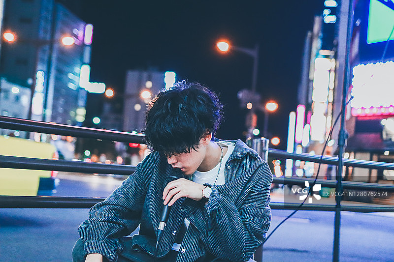 在夜晚的街道上表演的亚洲街头音乐家肖像图片素材