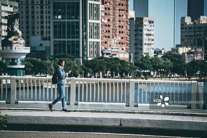 女人在街上边走边使用智能手机图片素材