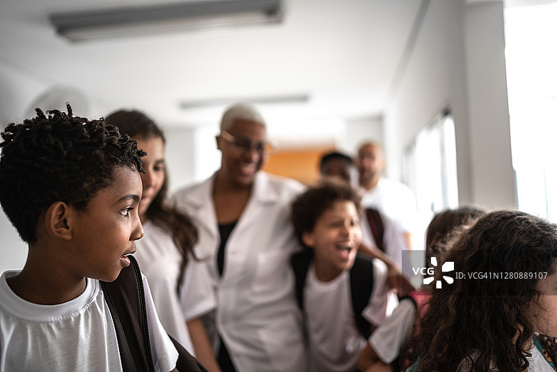 一群学生在学校走廊拥抱老师图片素材