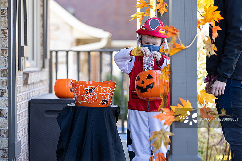 万圣节戴防护面具取糖果的男孩图片素材