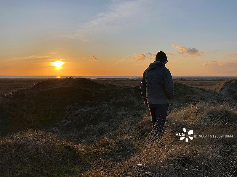 丹麦日德兰半岛：冬季在海滩上行走的男子背影图片素材