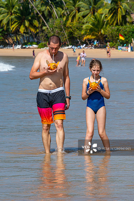 在斯里兰卡马特勒米瑞莎海滩喝椰汁的父女图片素材