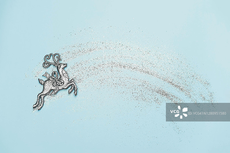 带有银色亮片和鹿雕像的浅蓝色背景图片素材