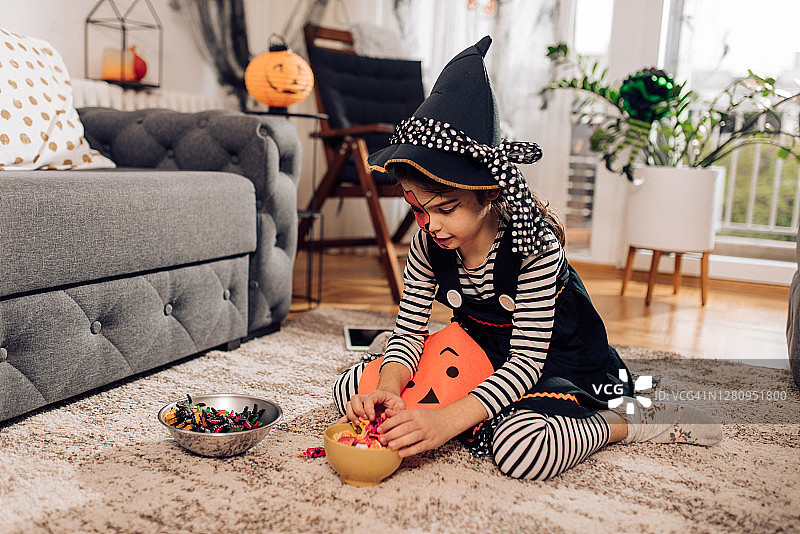 穿着万圣节服装吃糖果的可爱女孩图片素材