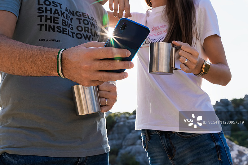 年轻情侣手捧咖啡看手机图片素材