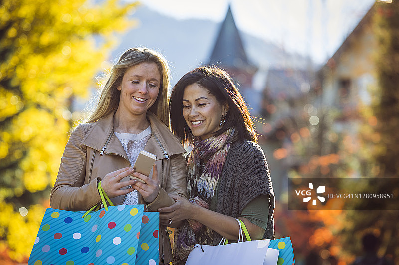 两位女人提着购物袋走过惠斯勒村图片素材