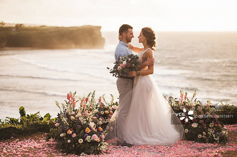 巴厘岛户外日落婚礼：年轻情侣拥吻图片素材