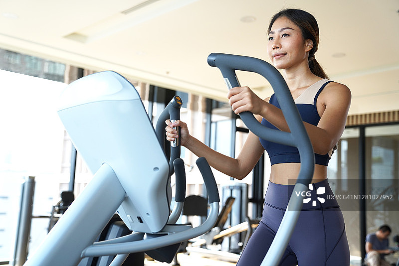 年轻女子在室内太空漫步椭圆机上锻炼图片素材