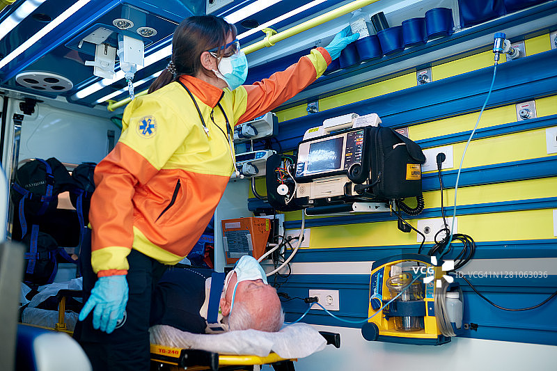 中年女护理人员调整设备，担架上躺着一位老年男子图片素材