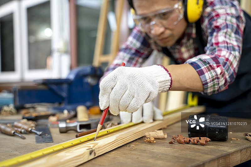 工人用卷尺和铅笔在木板上工作的细节图片素材