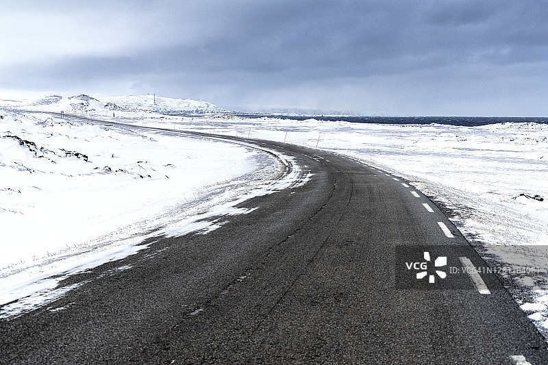 挪威芬马克北冰洋沿岸雪地中的空旷道路图片素材