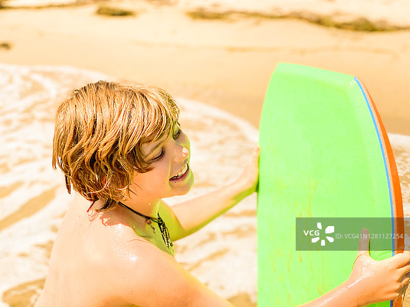 在加利福尼亚州圣巴巴拉海滩玩趴板的男孩图片素材
