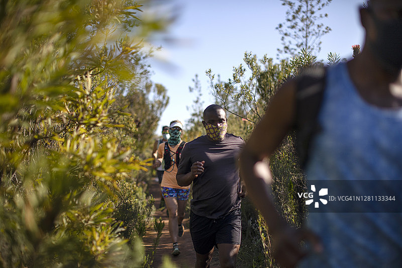 一群戴着口罩的朋友们在户外一起越野跑图片素材