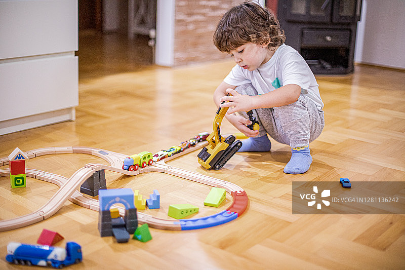 玩铁路火车玩具和塑料汽车的可爱小男孩图片素材