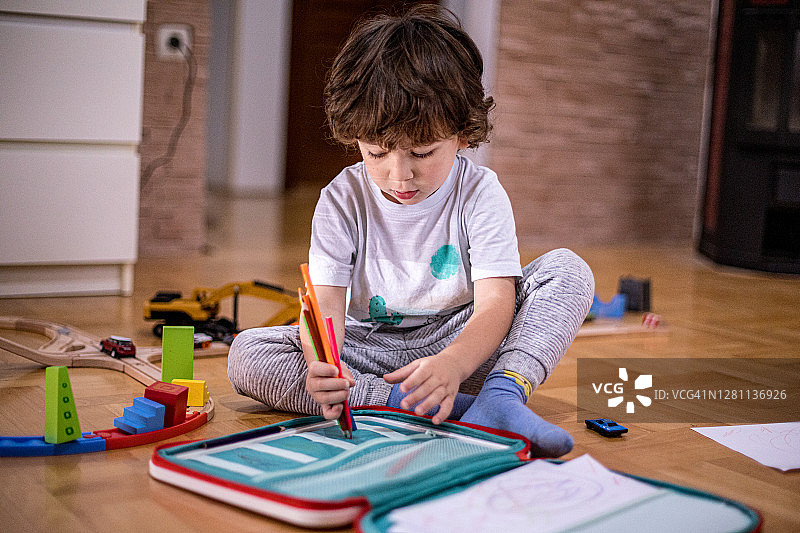 漂亮的小男孩用纸和蜡笔画画图片素材