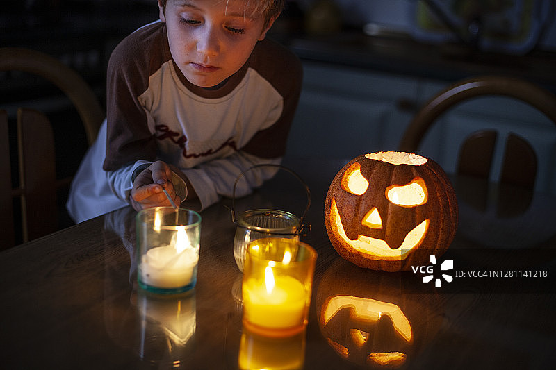 万圣节时，一个六岁男孩拿着南瓜和燃烧的蜡烛图片素材