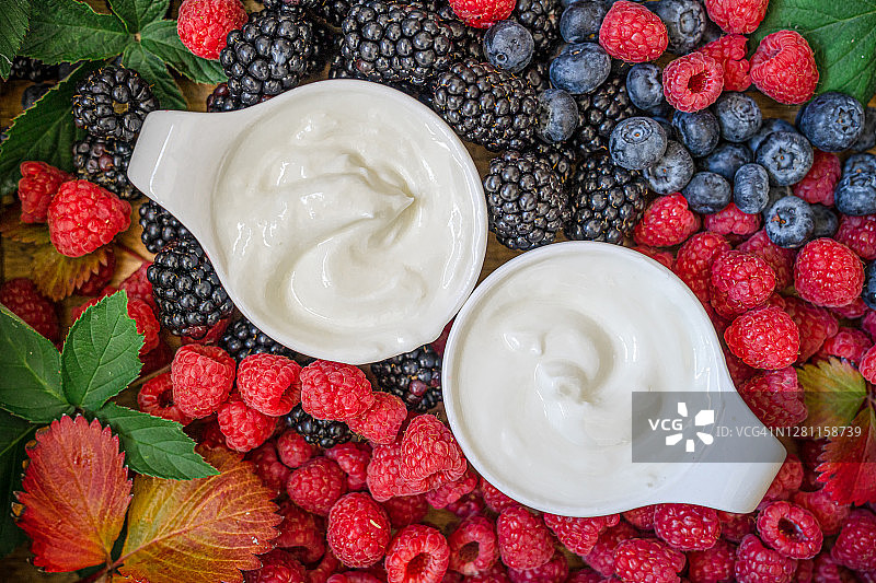 玻璃罐装希腊酸奶配勺子：新鲜希腊酸奶、麦片和浆果健康早餐图片素材
