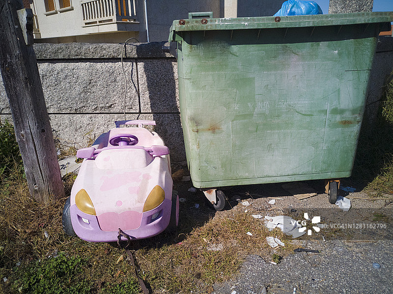 垃圾箱旁的废弃玩具车图片素材