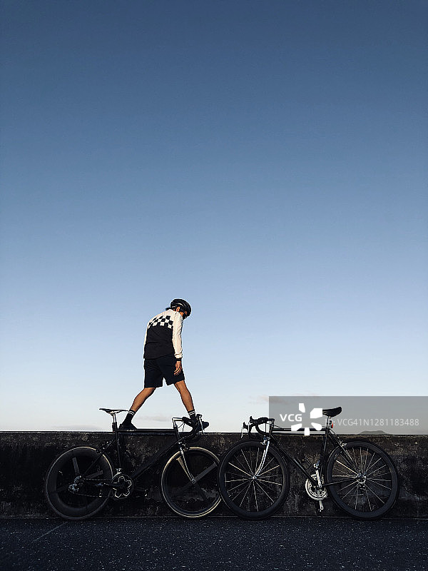 一位年轻的自行车手站在海滩附近，背景是天空和他的自行车图片素材