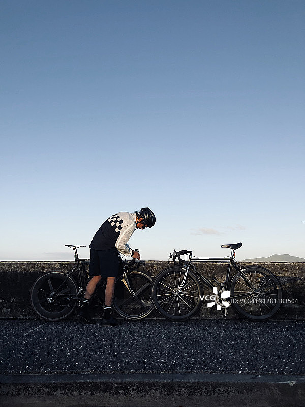 在海滩附近检查自行车的年轻自行车手图片素材