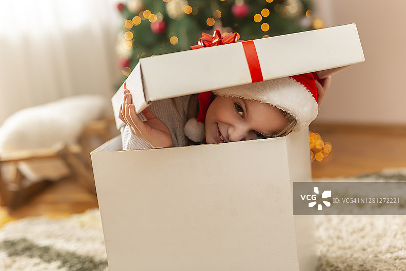 小女孩从巨大的圣诞礼物中探出头图片素材