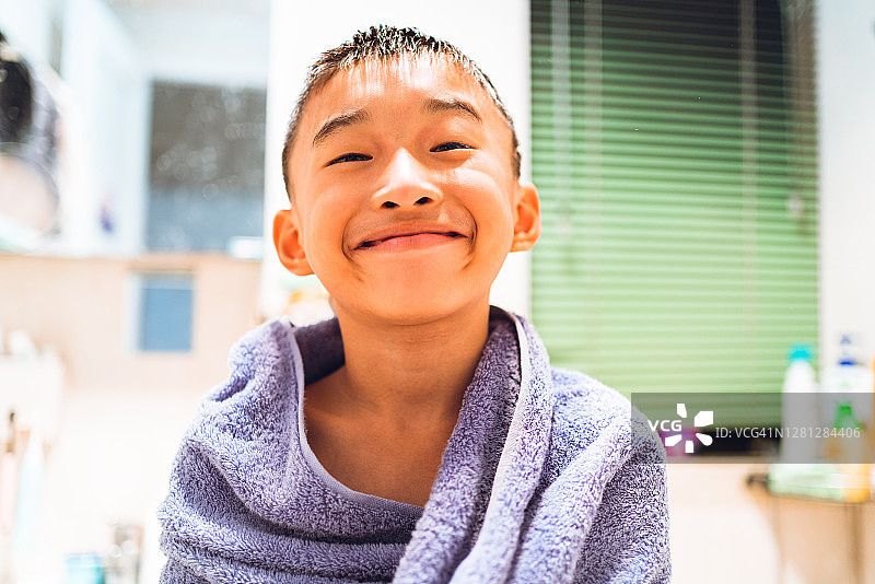 在卫生间披着浴巾的8岁小男孩图片素材