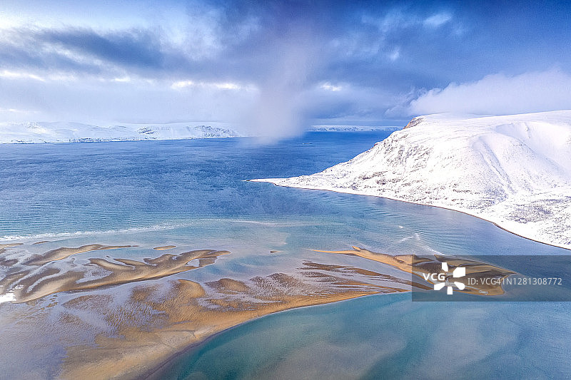 白雪皑皑的山脉和冰冷的北冰洋航拍，位于芬马克郡莱尔波伦图片素材