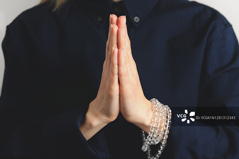 年轻女子手中的透明水晶念珠，练习瑜伽，双手合十，祈祷姿势，宗教信仰、祈祷、冥想和咒语重复的概念象征图片素材