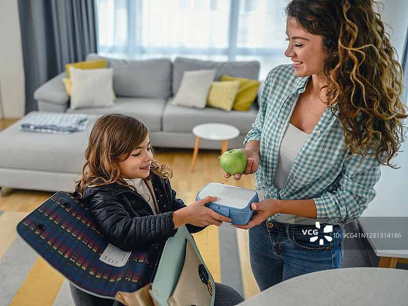 孩子从母亲手中接过午餐盒图片素材