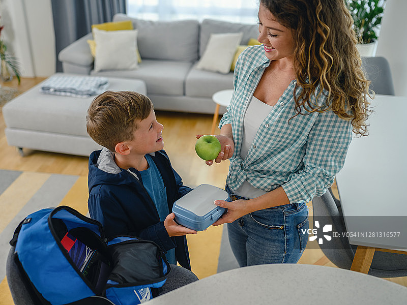 孩子从母亲手中接过午餐盒图片素材