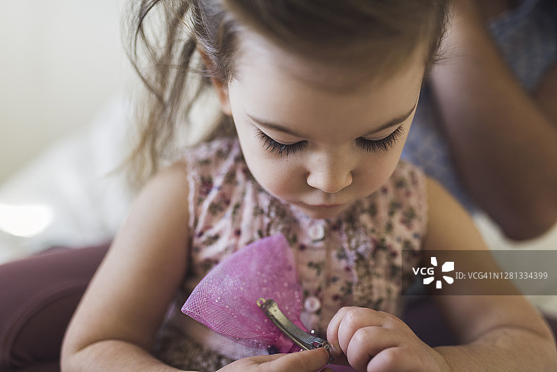好奇的4岁女孩看着发夹图片素材
