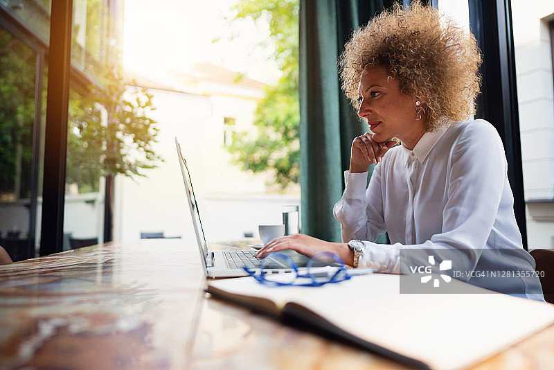 在餐厅用笔记本电脑工作的年长的白人女商人图片素材