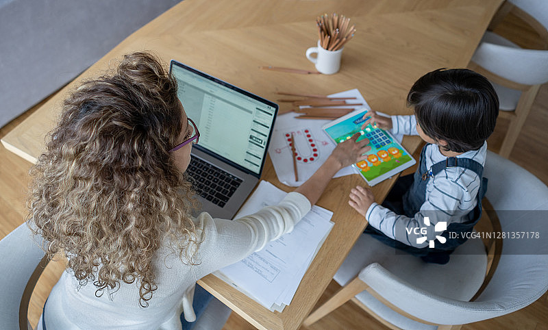 母亲在家工作时帮助儿子在家自学图片素材