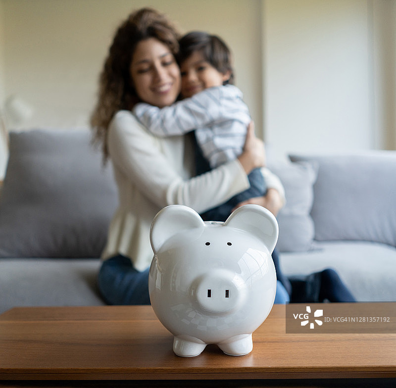 母亲和儿子把钱存入存钱罐后很开心图片素材