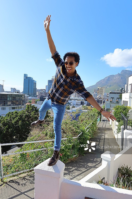 英俊的年轻男子在墙角的基石上保持平衡图片素材