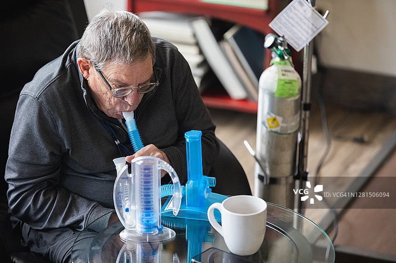 年长的男人使用一次性肺活量计锻炼肺部图片素材