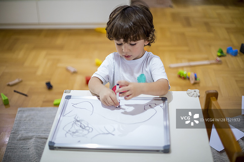 在白板上绘画的可爱幼儿男孩图片素材