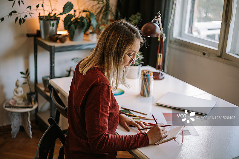 努力工作的年轻女人在笔记本上画草图图片素材